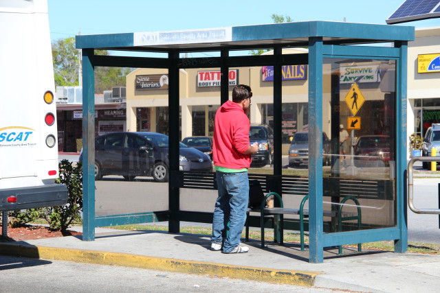 A person waits for a county bus at a shelter next to Southgate Mall in Sarasota. File photo