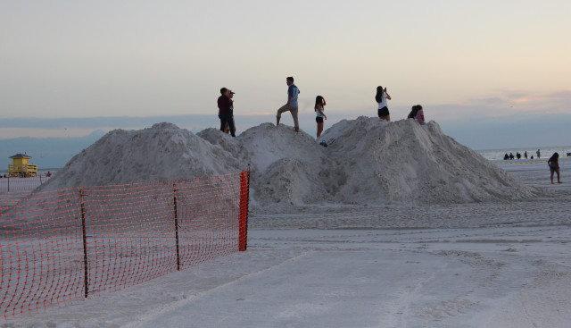 On Nov. 5, people stand atop piles of sand for the Crystal Classic sculptors as the sun sets on Siesta Key. Rachel Hackney photo