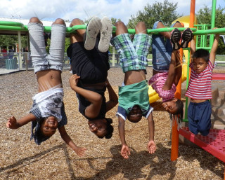 Children hang from the monkey bars at Newtown Estates Park. Image courtesy Sarasota County