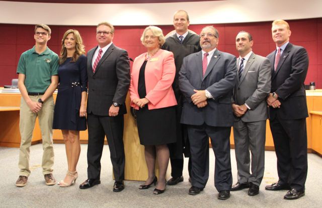 Following the ceremony, the commissioners all gather at the front of the chambers, along with Commissioner Mike Moran's son, Mikey (far left), and Moran's wife, Lori. Rachel Hackney photo